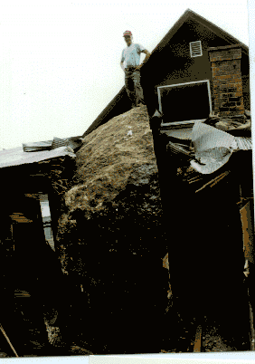 John Burt is standing on top of the boulder that rolled from a rock bluff face into the home in Fountain City, Wisconsin