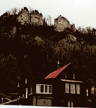 This photo shows the rock face from which the boulder fell into the home below (red roof).